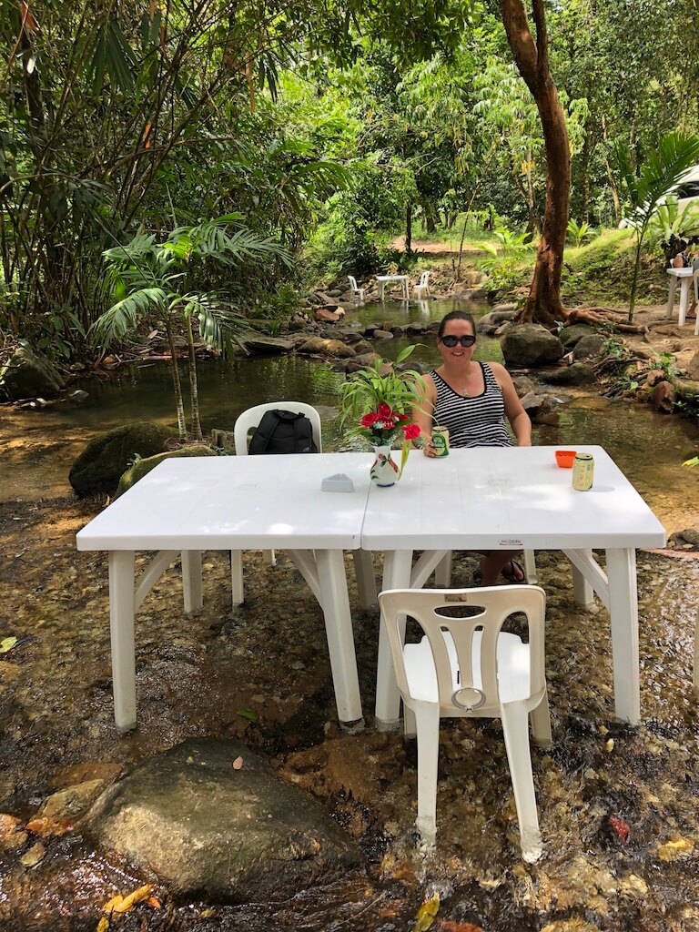 A person sat at a table with a beer in the middle of a river